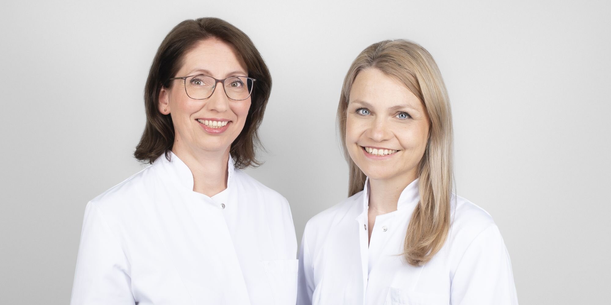 Zwei Ärztinnen im weißen Kittel stehen nebeneinander.