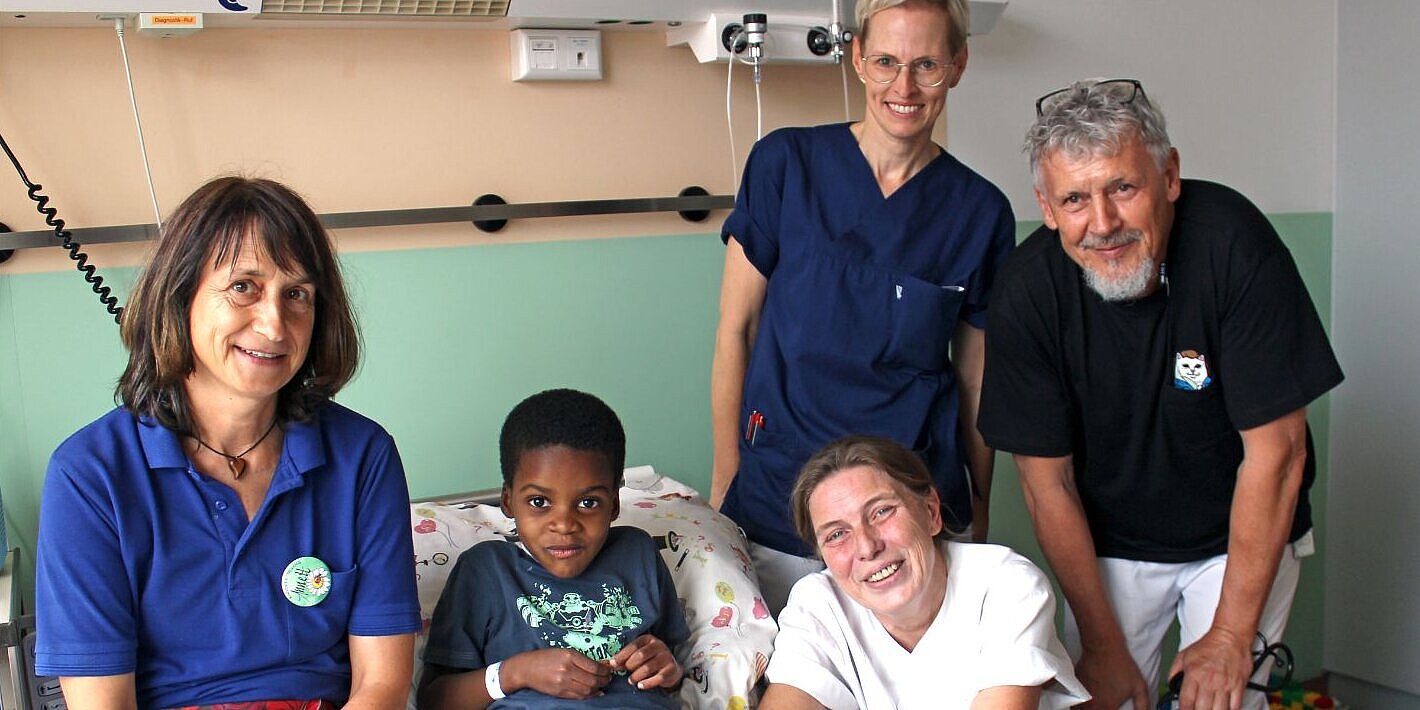 Sechsjähriger Junge sitzt im Krankenbett, neben ihm das Team des Wittenberger Krankenhauses.