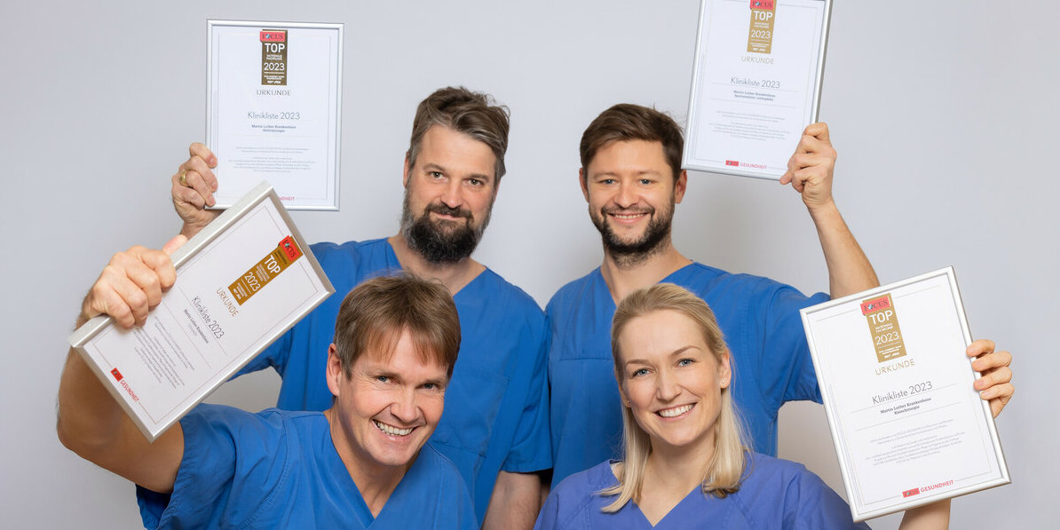 Vier Ärzt*innen halten gerahmte Auszeichnungen in den Händen und posieren für ein Gruppenbild.