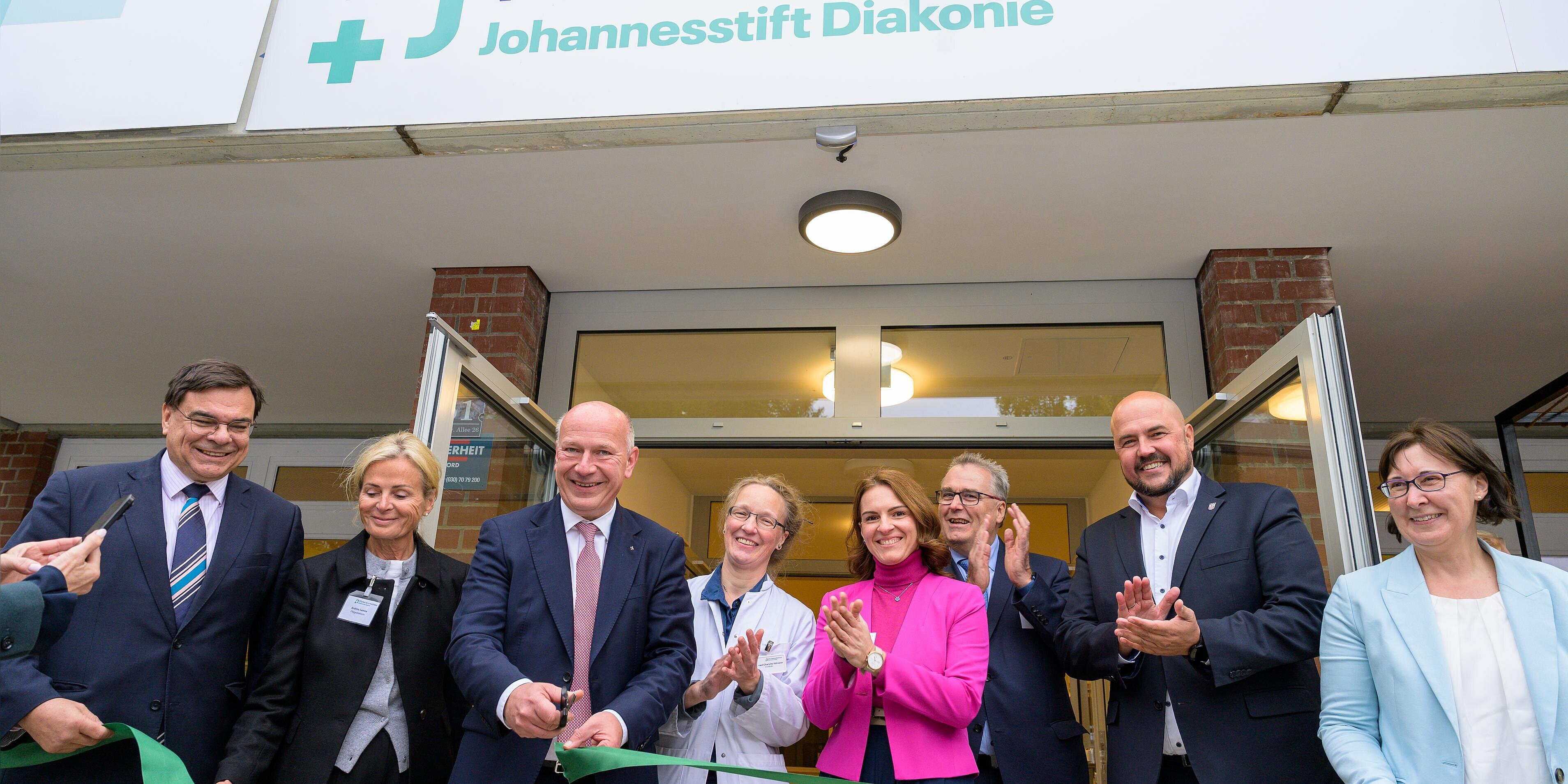 Bürgermeister zerschneidet Band zur feierlichen Eröffnung, neben ihm weitere Besucher*innen