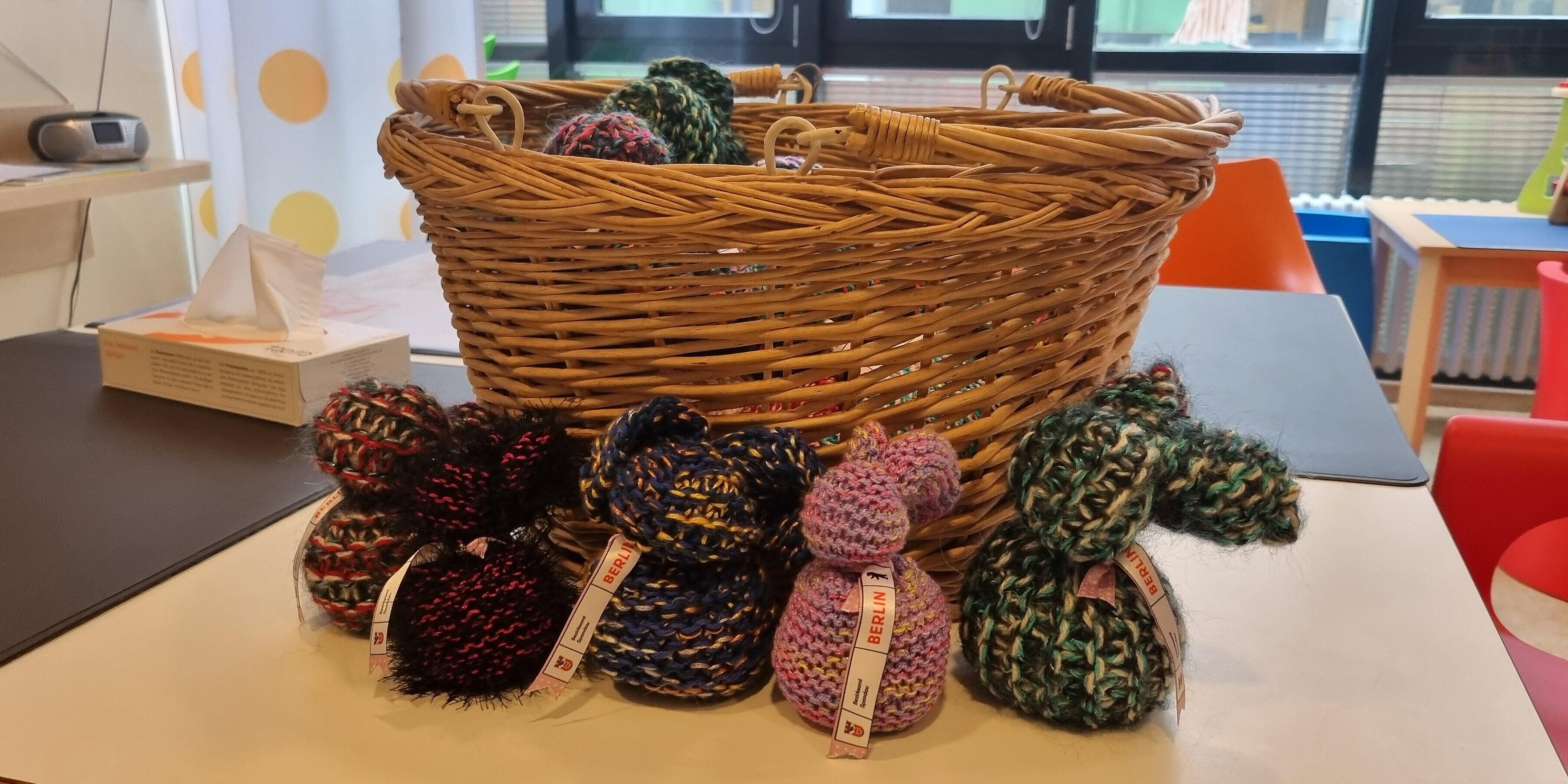 Osterhasen aus Wolle stehen vor einem Osterkörbchen