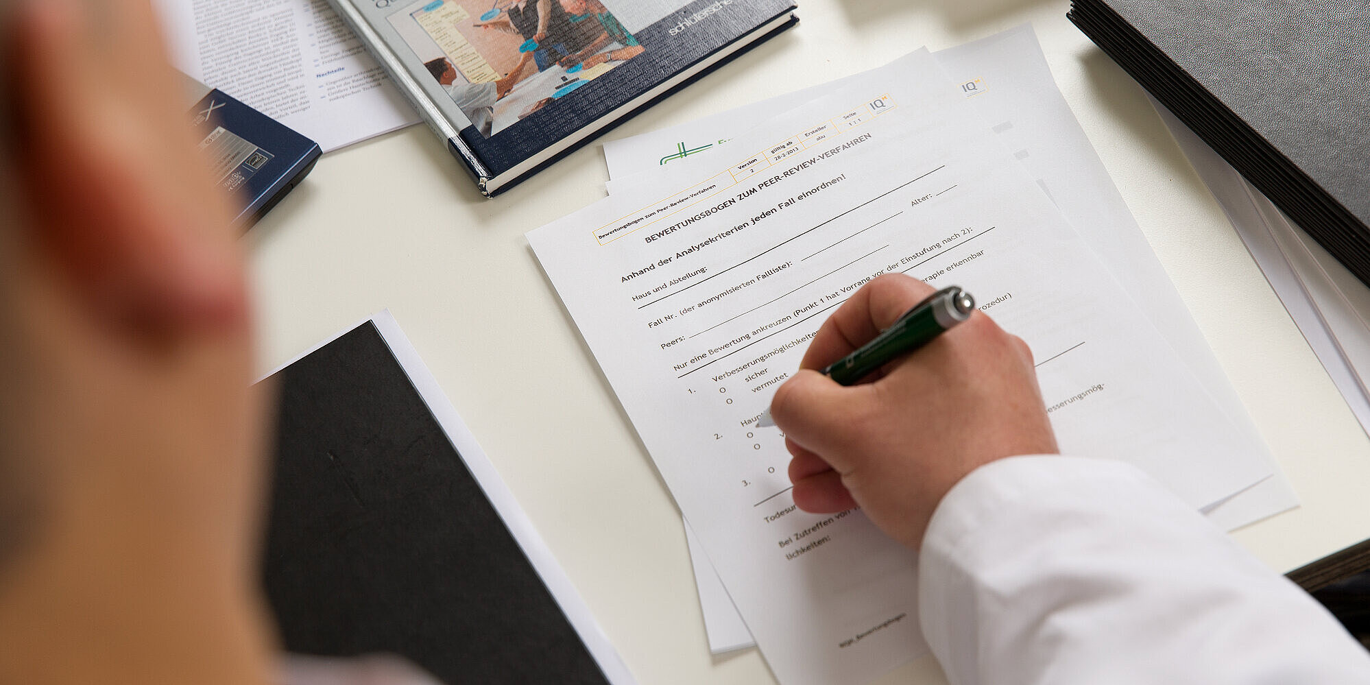 Mitarbeiter füllt einen auf dem Tisch liegenden Fragebogen aus.