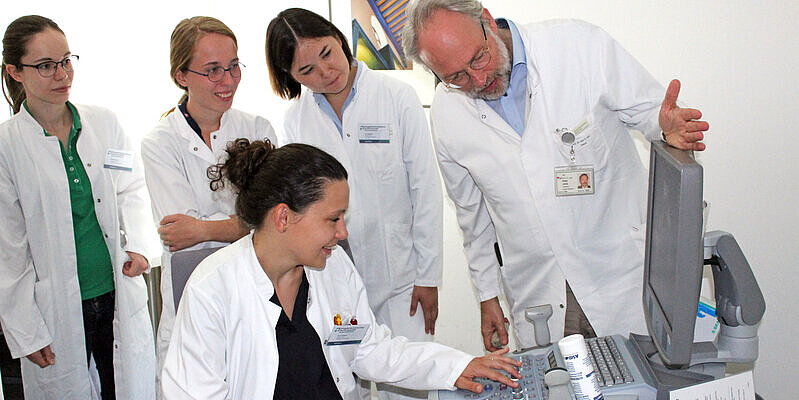 Fünf Ärzt*innen schauen auf einen Ultraschall-Monitor