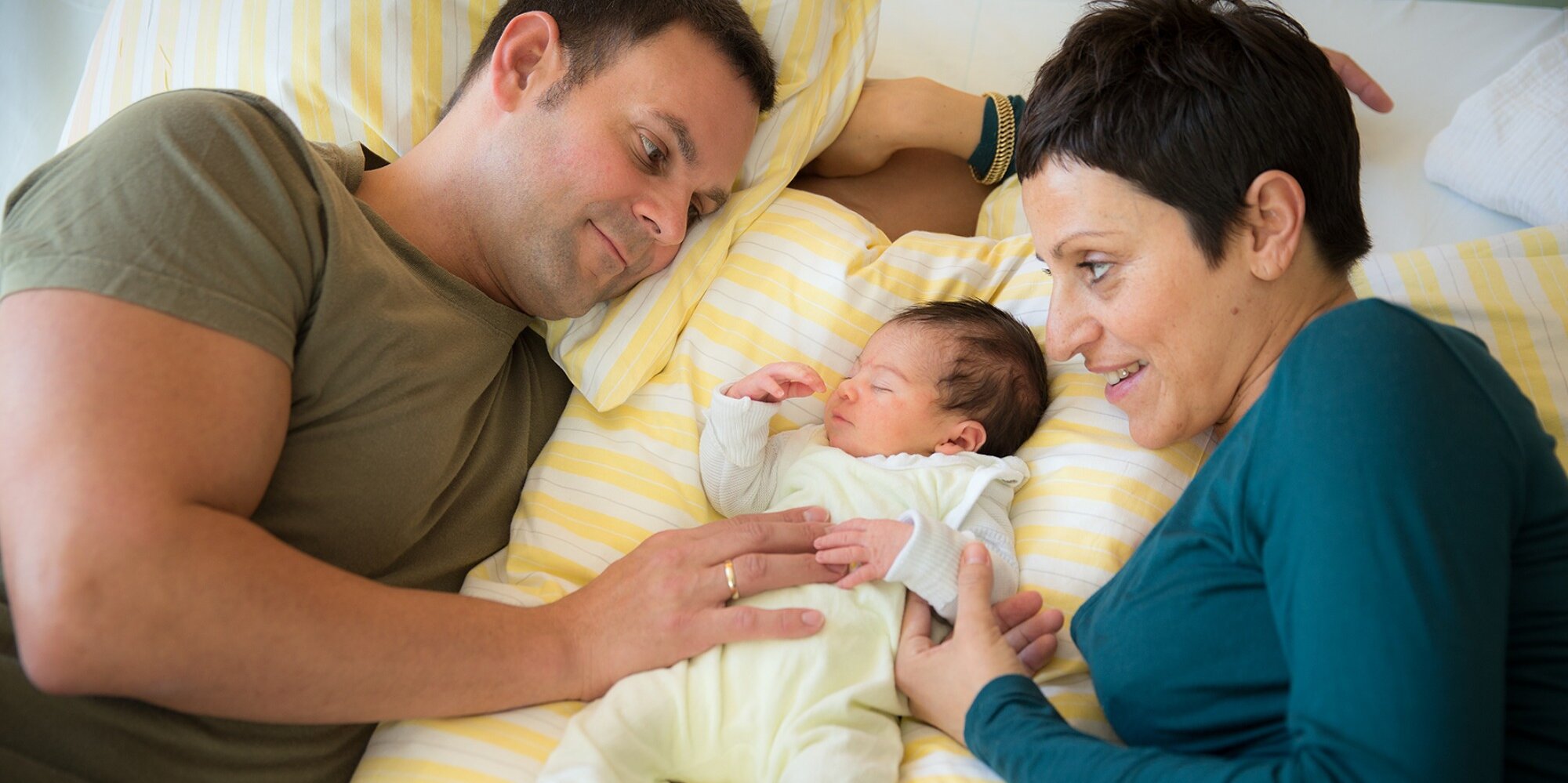 Vater und Mutter liegen Bett des Familienzimmers mit ihrem Neugeborenen.