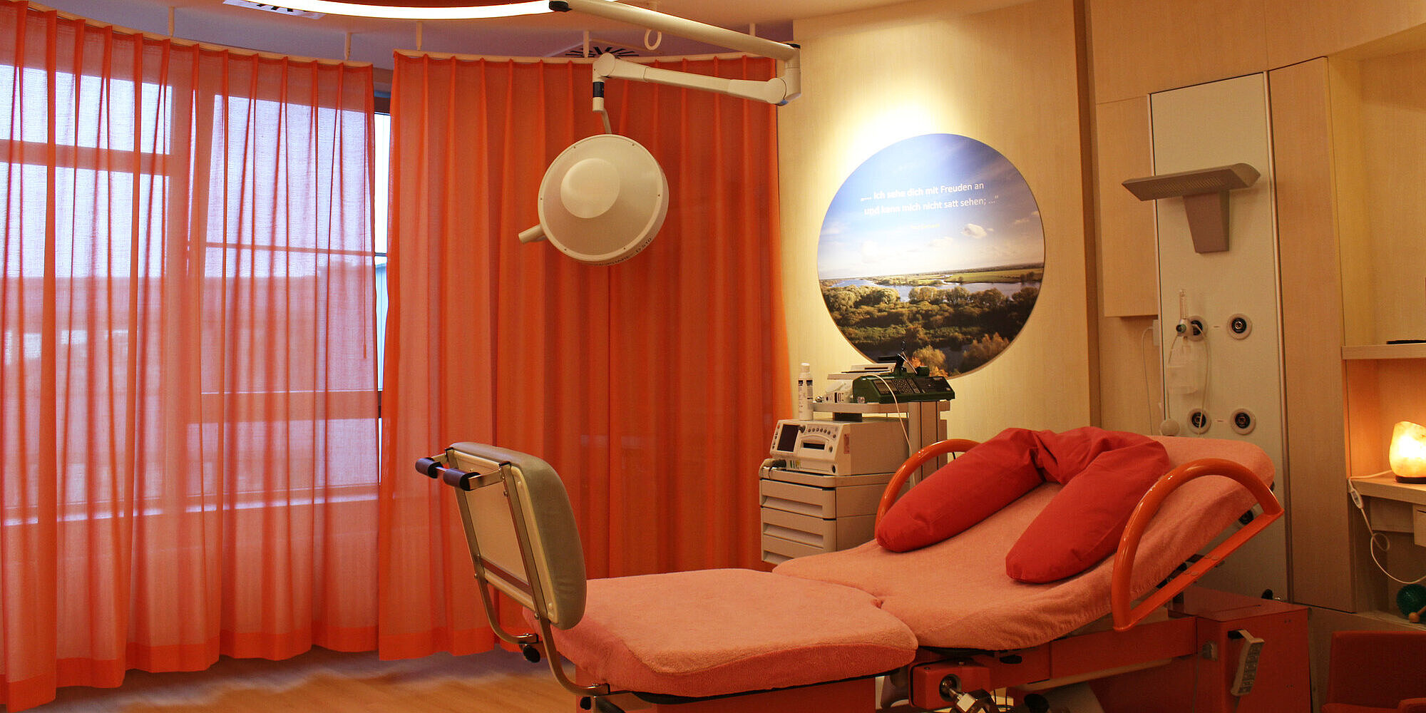 Kreißsaal mit Bett und roten Vorhängen
