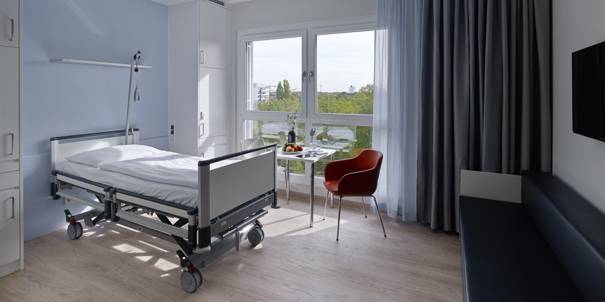 Blick in ein modern eingerichtetes Komfortzimmer mit Schlafsofa und Pflegebett im Martin Luther Krankenhaus