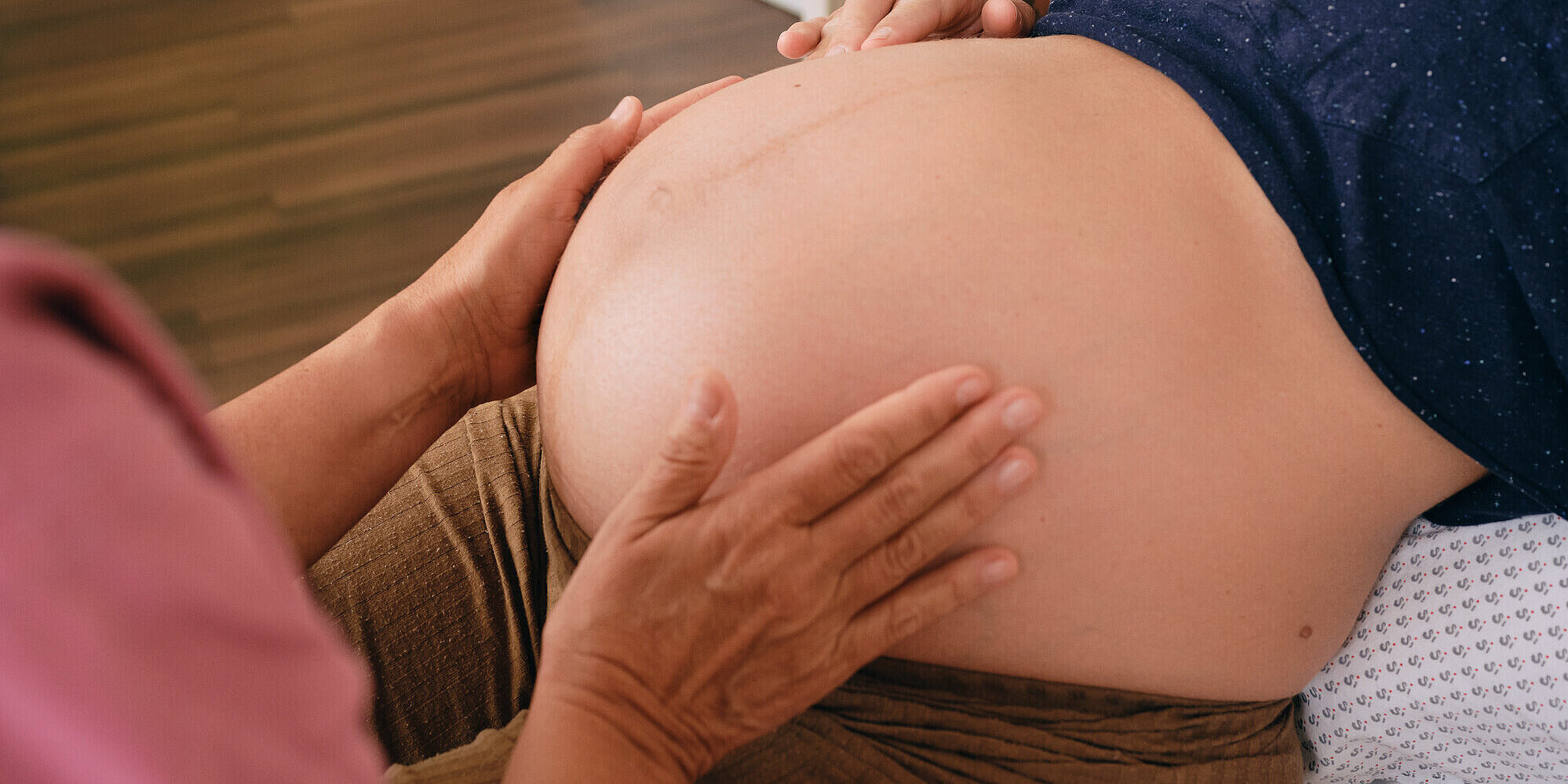 Schwangere im Kreißsaal Bauch einer schwangeren Frau im Kreißsaal der von einer Hebamme abgetastet wird
