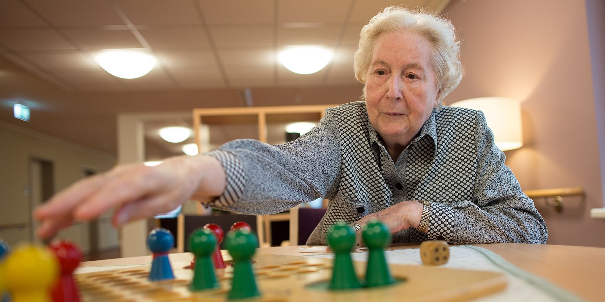Eine ältere Dame spielt ein seniorengerechtes Brettspiel.