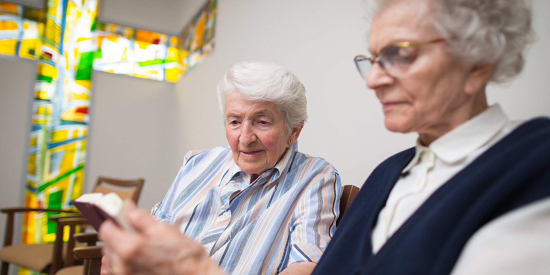 Zwei ältere Frauen lesen in der Kapelle gemeinsam in der Bibel.