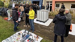 Viele Menschen bauen auf einer Wiese gemeinsam einen nachhaltigen Kompost.