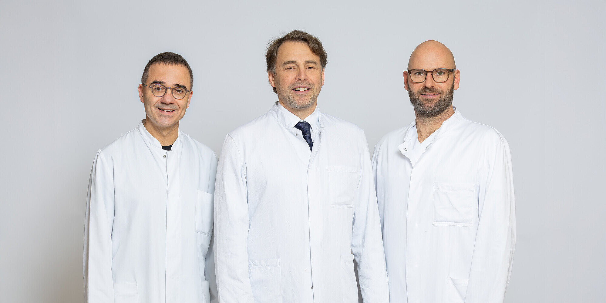 Dr. med. Torsten Heldmann, Leitender Angiologe, Klinik für Angiologie; PD Dr. med. Christian Rosenberg, Chefarzt Klinik für Bildgebende Diagnostik und Interventionsradiologie; Dr. med. Max Thiemann, Chefarzt Klinik für Gefäß- & Endovaskularchirurgie Drei Männer in Arztkittel stehen nebeneinander