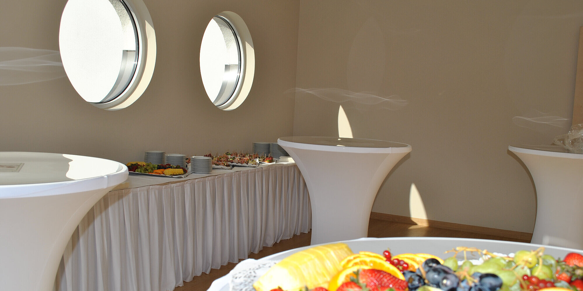 Blick in einen Veranstaltungsräum mit Buffet und Stehtischen.