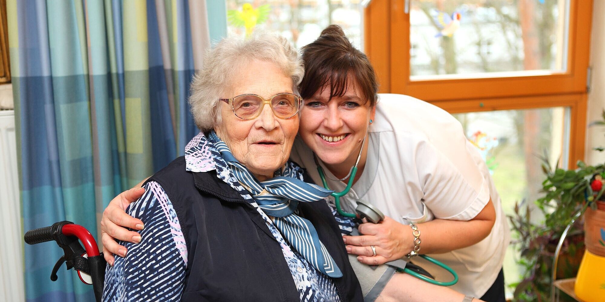 Zugewandte Pflegerin misst den Blutdruck einer Bewohnerin.