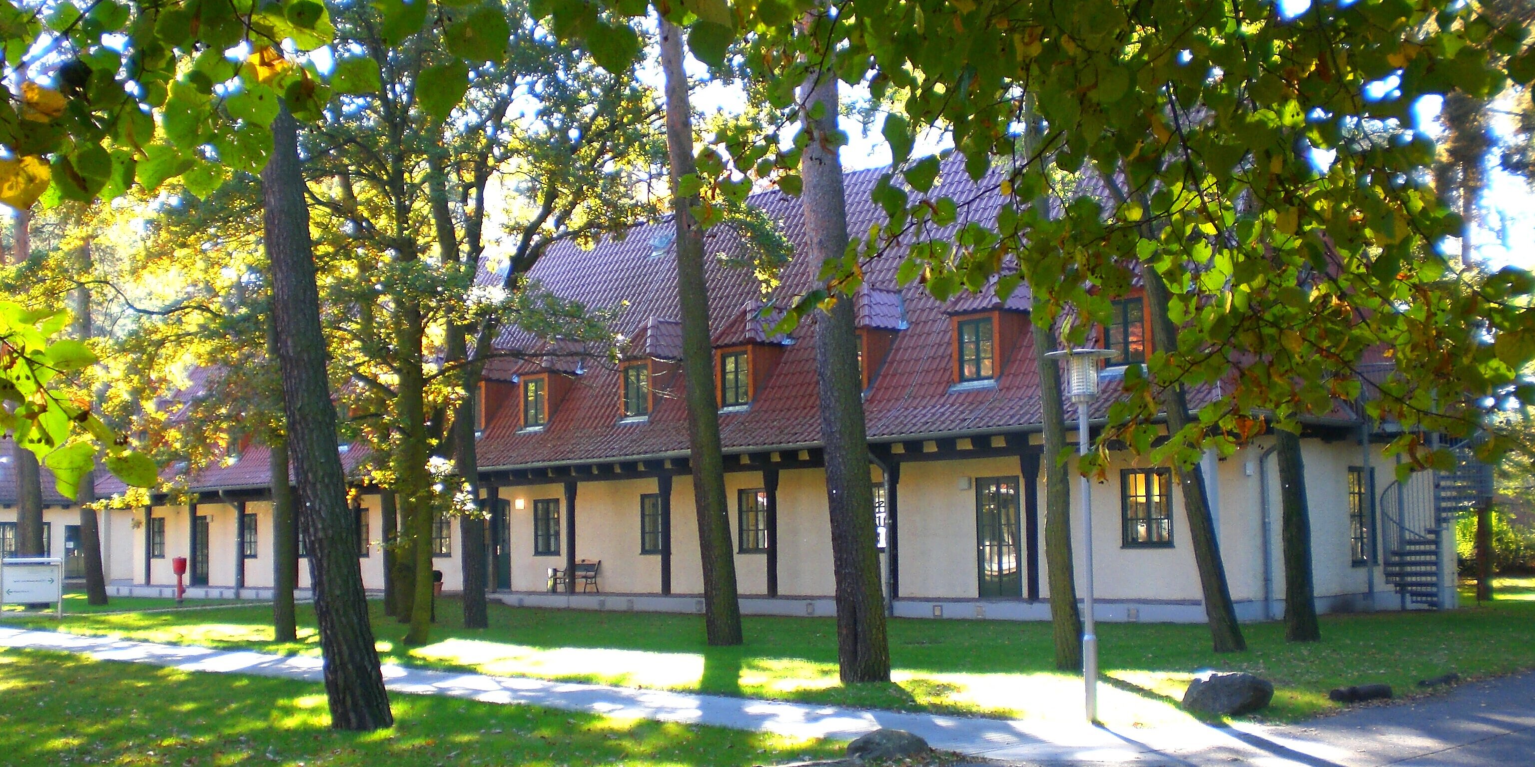 Bäume vor einem Gebäude mit rotem Dach