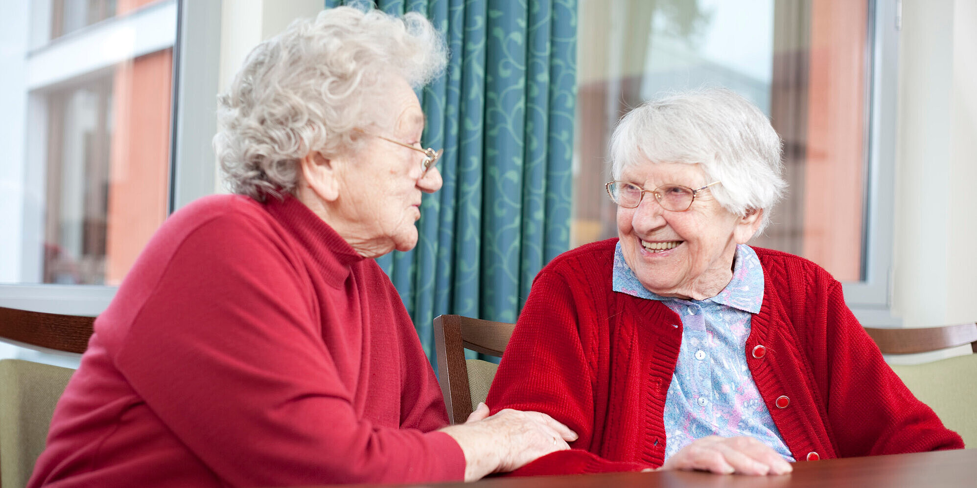 Zwei Bewohnerinnen unterhalten sich und lachen gemeinsam.