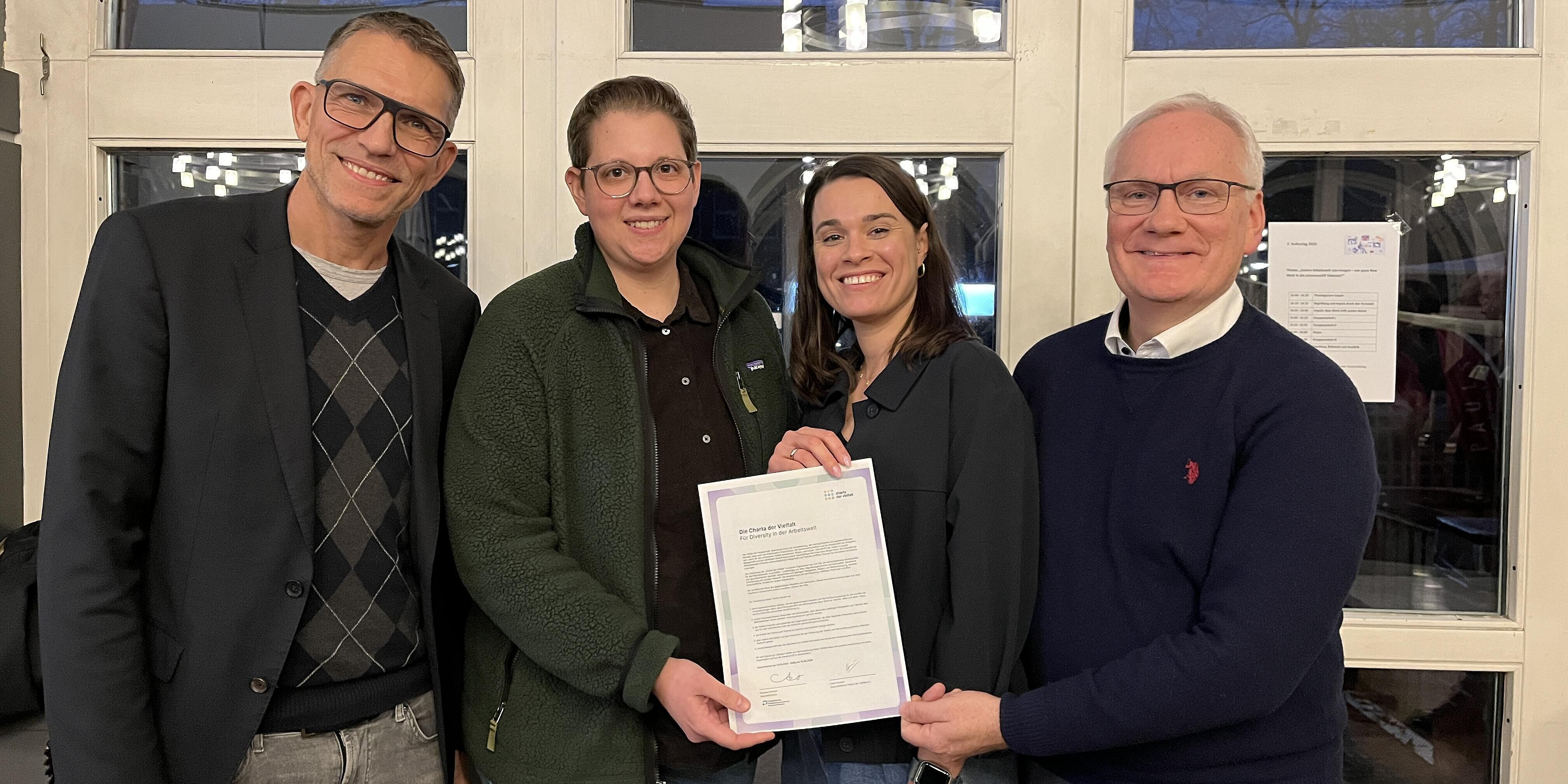 Vier Mitarbeitende des Krankenhauses präsentiere die unterzeichnete Urkunde zur Charta der Vielfalt.