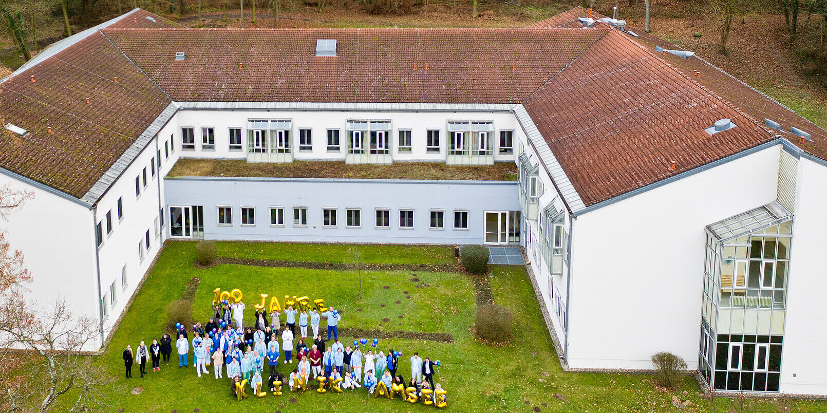 Gruppenfoto mit Luftballons vor Gebäude