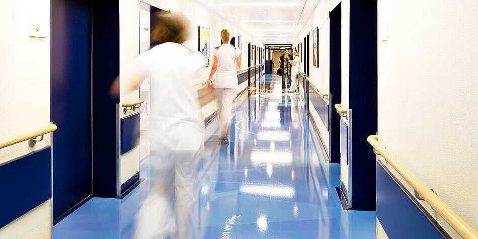 Zwei Mitarbeitende rennen über den Stationsflur der Klinik für MIC.
