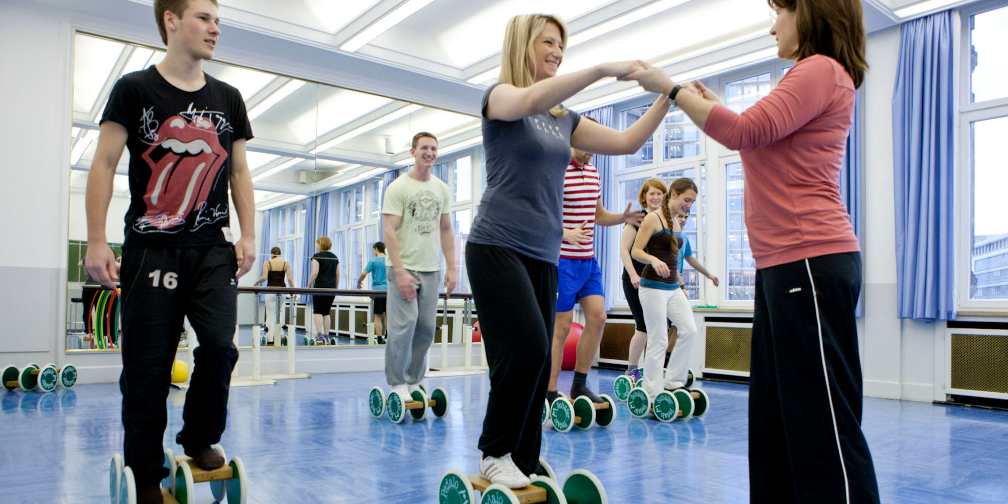 Eine intensive Lernbegleitung bieten dir bestmögliche Startbedingungen als Physiotherapeut*in. Lehrerin hält Schülerin an den Händen bei einer Gleichgewichtsübung.
