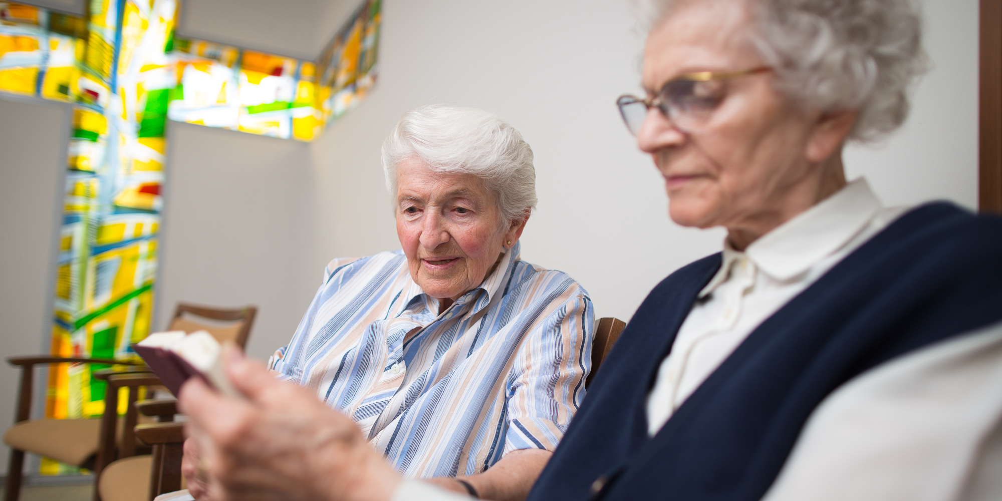 Zwei ältere Frauen lesen in der Kapelle gemeinsam in der Bibel.