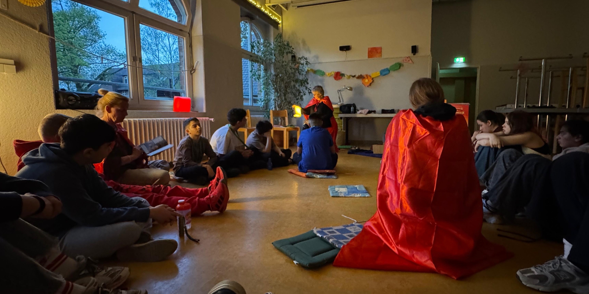 Kinder sitzen im Kreis und lauschen der Vorleserin